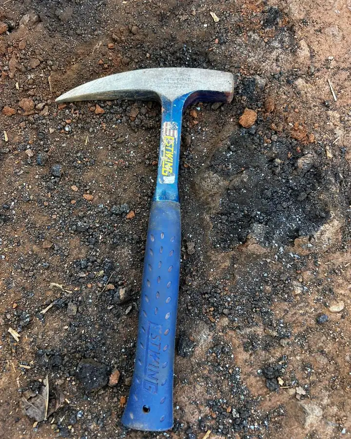 Martelo de geólogo de cabo azul deitado sobre o solo